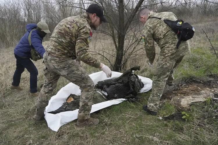Ukrainian servicemen pack the dead body of a Russian soldier, killed in a recent battle in the Kharkiv region, Ukraine, Saturday, April 8, 2023. 